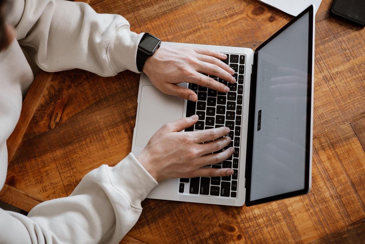 Hands typing on a laptop at a wooden desk